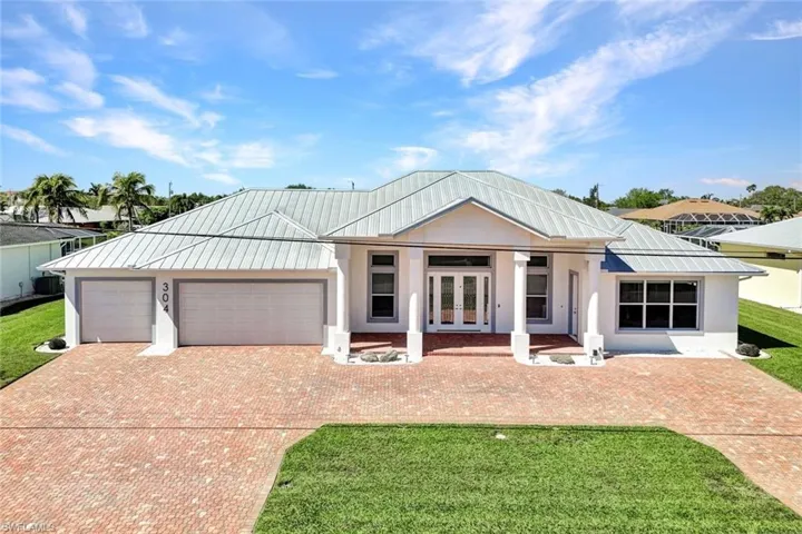 View of front of home featuring a front yard, stucco siding, french doors, metal roof, and an attached garage