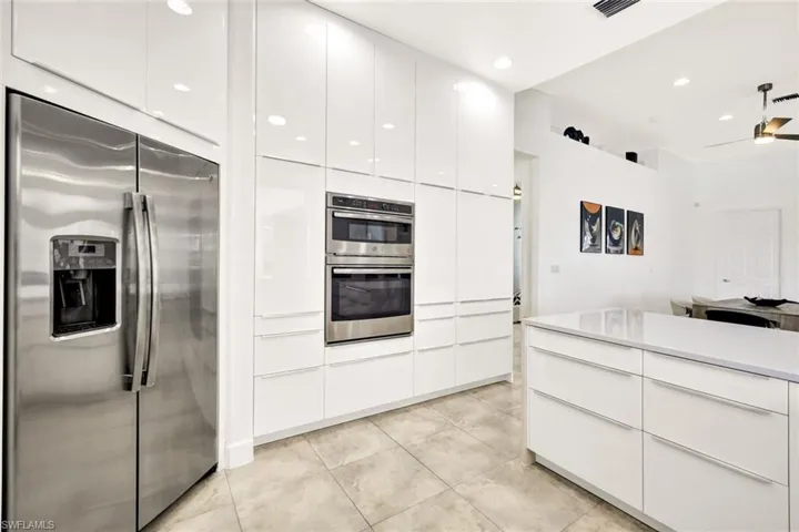 Kitchen featuring ceiling fan, appliances with stainless steel finishes, light tile patterned flooring, white cabinets, and modern cabinets