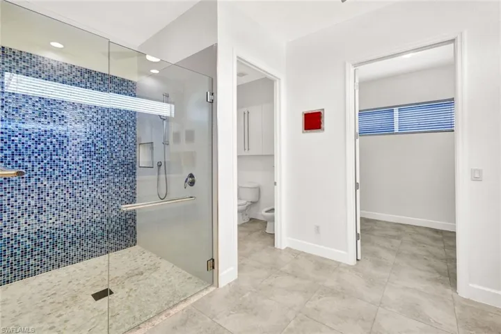 Bathroom featuring tile patterned flooring, a shower stall, toilet, and baseboards