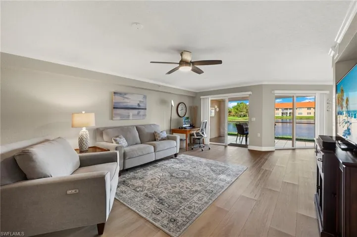 Living room featuring ceiling fan, light hardwood / wood-style flooring, crown molding, and water views