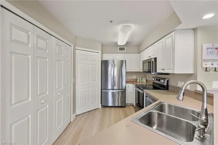 Kitchen featuring white cabinetry, sink, stainless steel appliances, and light hardwood / wood-style floors