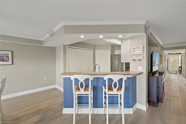 Kitchen featuring a breakfast bar, stainless steel fridge, light wood-type flooring, and kitchen peninsula