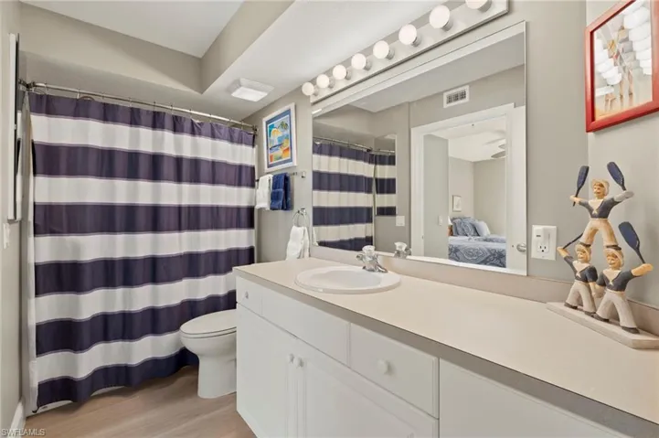 Second bathroom with a shower with curtain, vanity, hardwood / wood-style flooring, and toilet