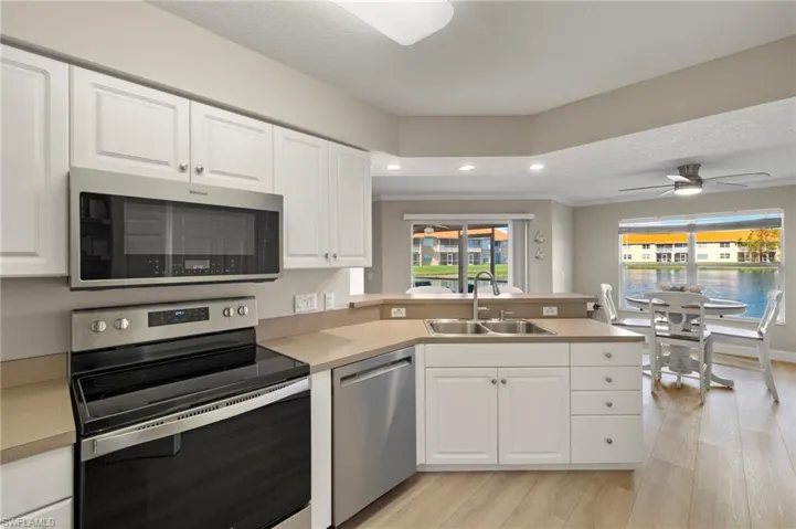 Kitchen with white cabinets, appliances with stainless steel finishes, a healthy amount of sunlight, and a double sink with garbage disposal