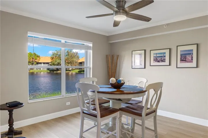 Dining area featuring ceiling fan, crown molding, a water view, and light wood-type flooring