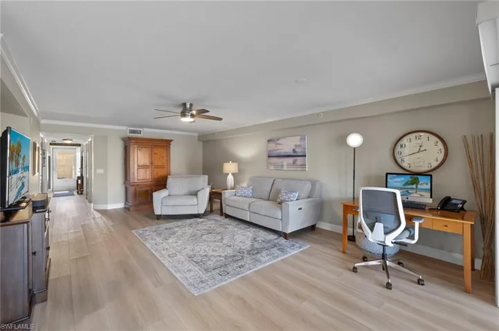 Living room with ceiling fan, ornamental molding, and light wood-type flooring