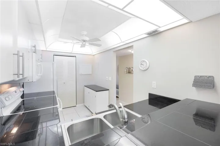Kitchen with white range with electric cooktop, sink, light tile patterned floors, and ceiling fan