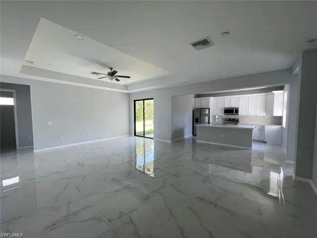 Unfurnished room featuring a tray ceiling, ceiling fan, and sink