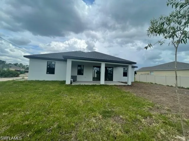 Rear view of property with a lawn and a patio