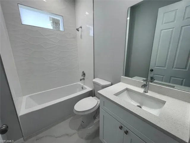Full bathroom with tiled shower / bath, vanity, and toilet