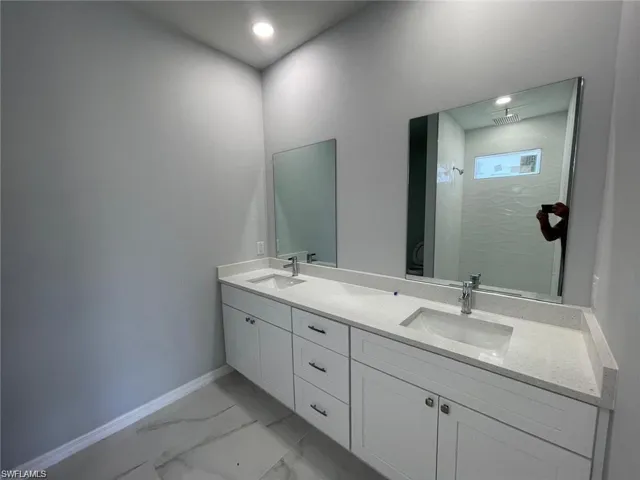 Primary Bathroom featuring a tile shower and vanity