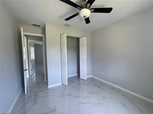 Unfurnished bedroom with ceiling fan and a closet