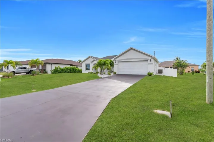 Single story home with driveway, stucco siding, a front lawn, and an attached garage