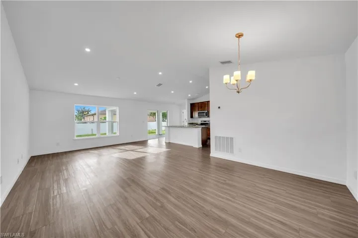 Unfurnished living room featuring lofted ceiling, light wood-style flooring, recessed lighting, and a chandelier