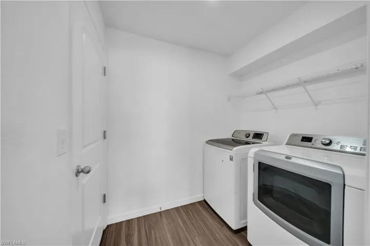 Laundry area with dark wood finished floors and washer and clothes dryer
