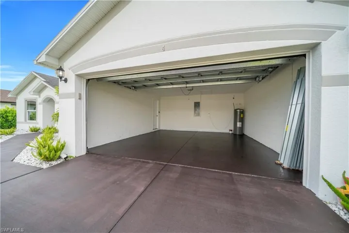 Garage featuring electric water heater, concrete driveway, and electric panel