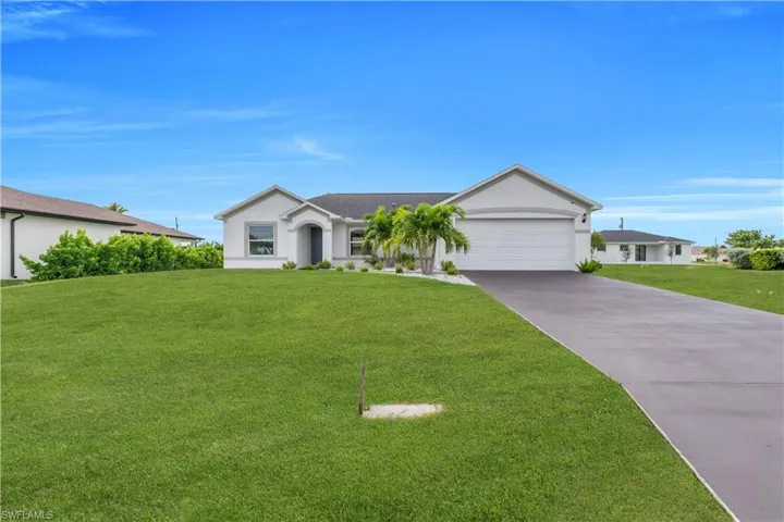 Ranch-style house featuring a front lawn, driveway, stucco siding, and an attached garage