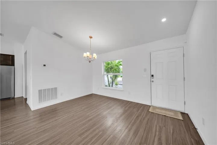 Foyer entrance with wood finished floors, a chandelier, recessed lighting, and vaulted ceiling