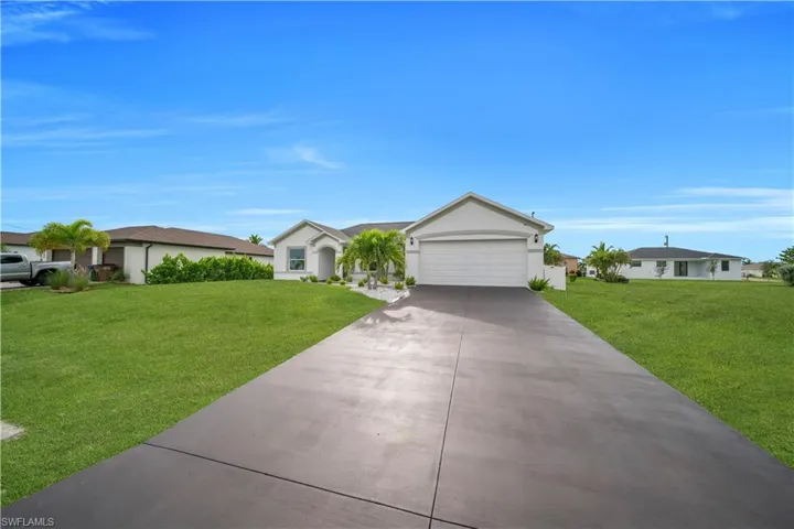 Single story home with a front lawn, concrete driveway, and stucco siding