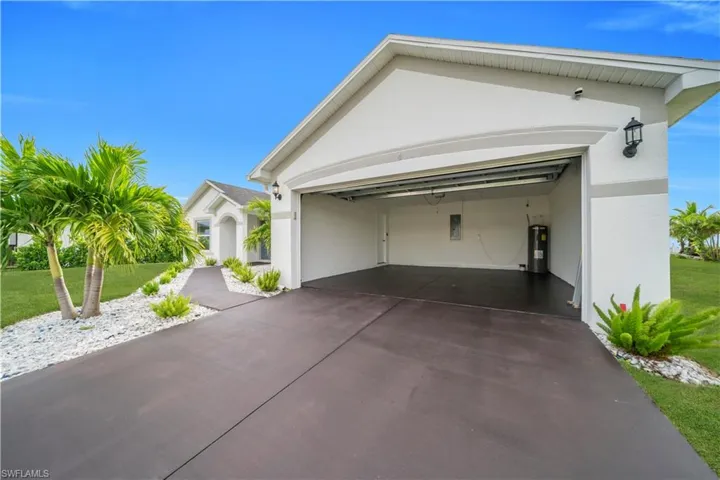 View of front of property featuring a garage, stucco siding, a front lawn, and driveway
