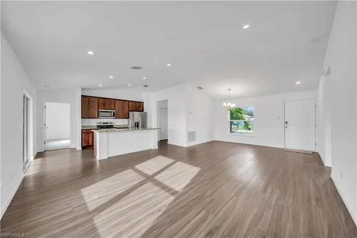 Unfurnished living room featuring lofted ceiling, light wood-style floors, recessed lighting, and a chandelier