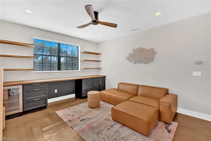 Office space featuring built in study area, wine cooler, ceiling fan, light wood finished floors, and recessed lighting
