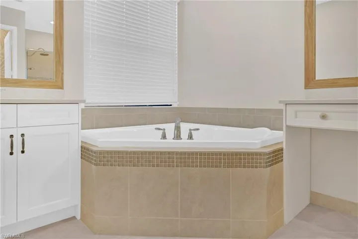 Full bath with vanity, a garden tub, and light tile patterned floors