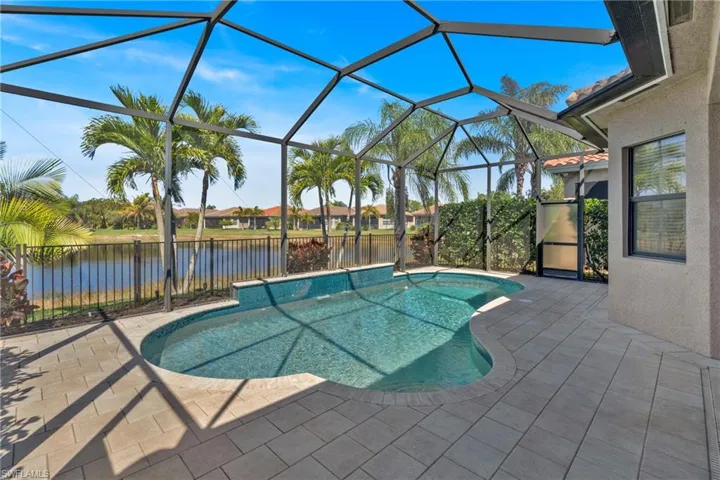 View of pool with patio surround, a sunroom, a lanai, a fenced backyard, and a water view
