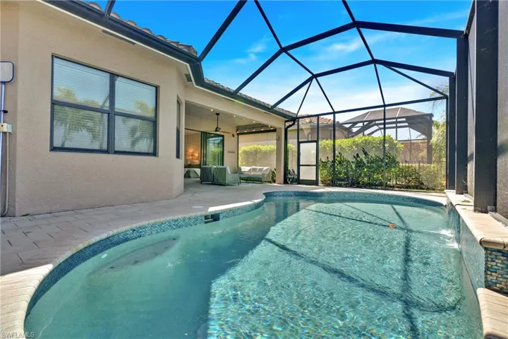 Outdoor pool with a patio area, a sunroom, glass enclosure, and an outdoor living space