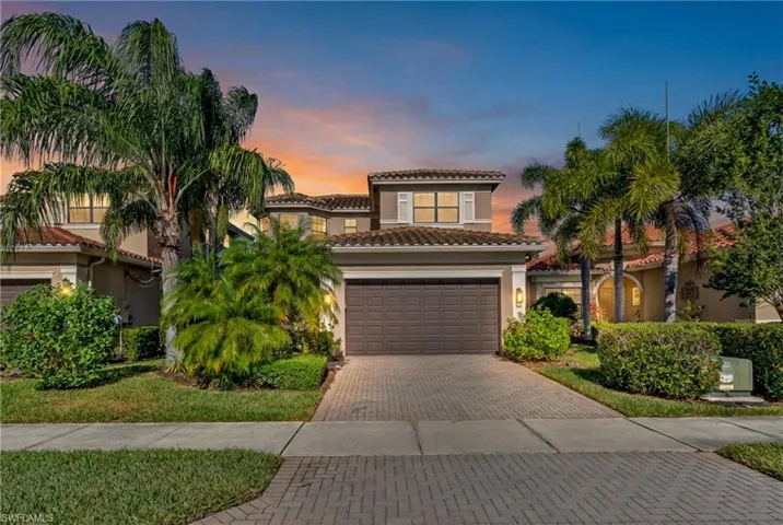 Mediterranean / spanish house with decorative driveway, stucco siding, a tile roof, a front lawn, and an attached garage