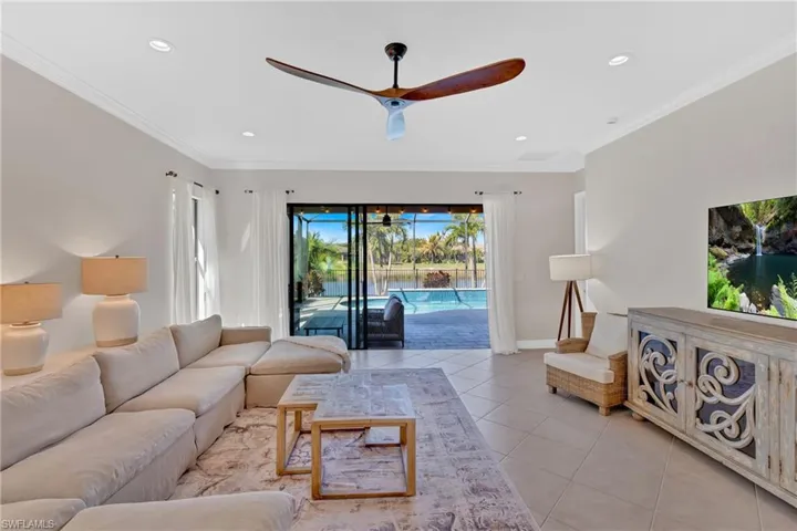 Living area with ceiling fan, a sunroom, light tile patterned floors, crown molding, and recessed lighting