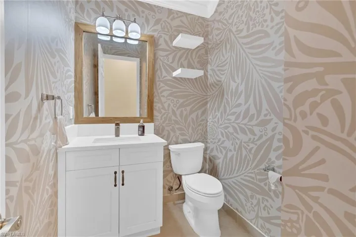 Bathroom featuring wallpapered walls, vanity, light tile patterned floors, and crown molding