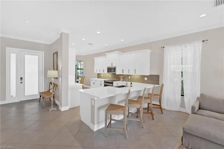 Kitchen with a peninsula, white cabinetry, a breakfast bar area, crown molding, and tasteful backsplash