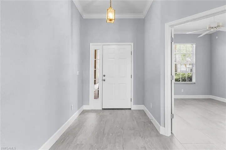 Entrance foyer featuring ornamental molding, light wood finished floors, and a ceiling fan