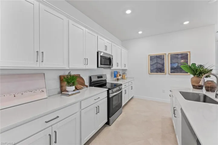 Kitchen with appliances with stainless steel finishes, light countertops, white cabinets, and recessed lighting