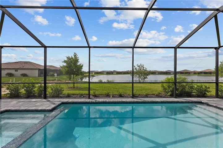 View of swimming pool featuring a lanai, a water view, and a pool with connected hot tub