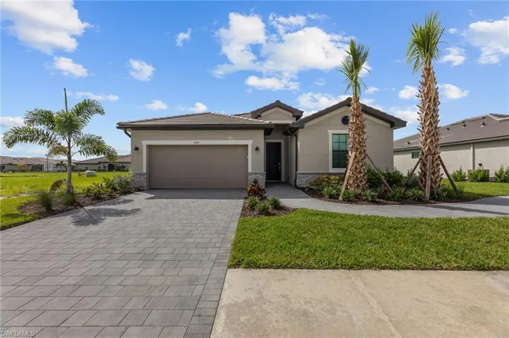 View of front of house featuring stucco siding, a garage, decorative driveway, and a front lawn