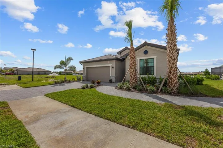 View of front of property featuring stucco siding, driveway, a garage, a front yard, and stone siding