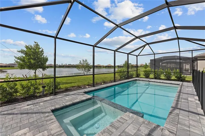 View of pool featuring a pool with connected hot tub, a water view, a patio, a residential view, and a lanai