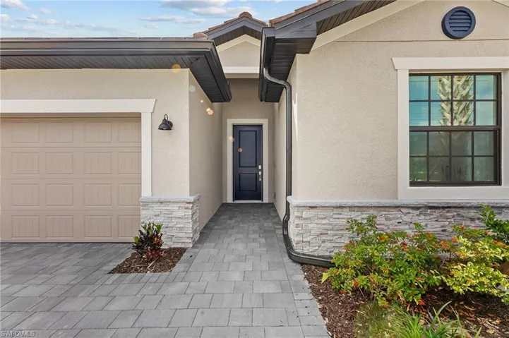 View of exterior entry featuring stone siding, stucco siding, and a garage