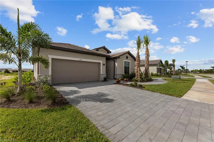 Ranch-style home with stucco siding, an attached garage, decorative driveway, a tiled roof, and stone siding