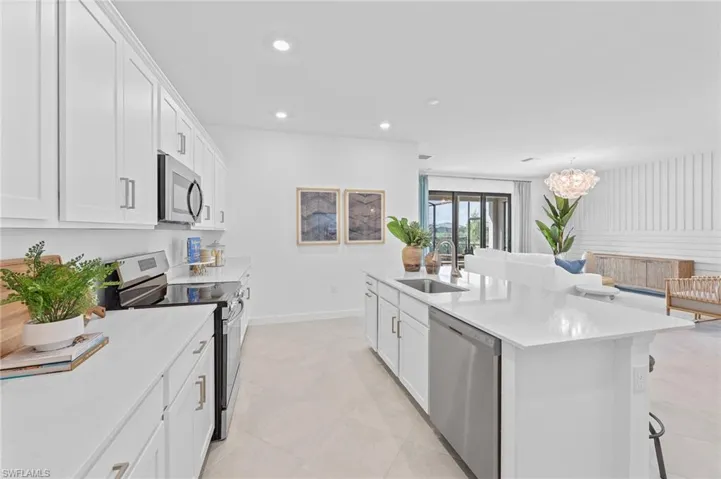 Kitchen with appliances with stainless steel finishes, light countertops, white cabinets, recessed lighting, and a center island with sink