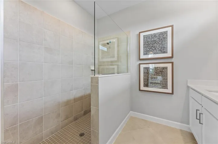 Bathroom with walk in shower, vanity, and tile patterned floors