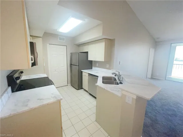 Kitchen with white cabinetry, appliances with stainless steel finishes, light carpet, sink, and kitchen peninsula