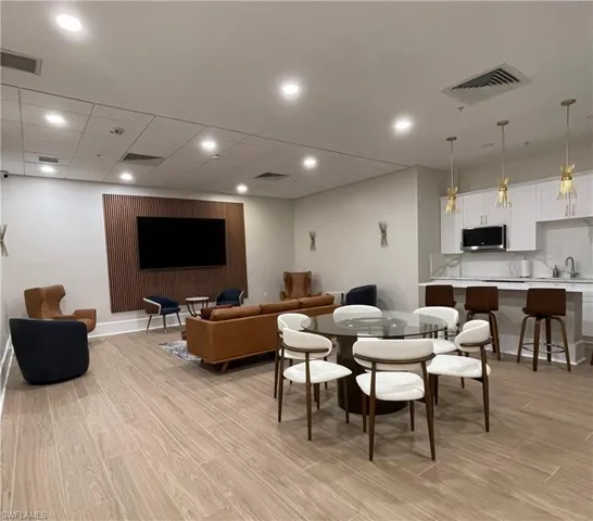 Community entertainment room with large screen TV, dining area & kitchen.