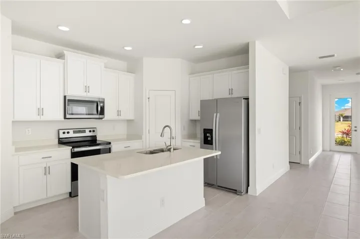 Kitchen featuring an island with sink, a sink, appliances with stainless steel finishes, and white cabinets