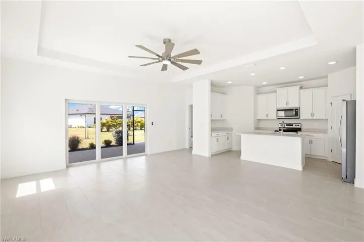 Unfurnished living room featuring a sink, a raised ceiling, and ceiling fan