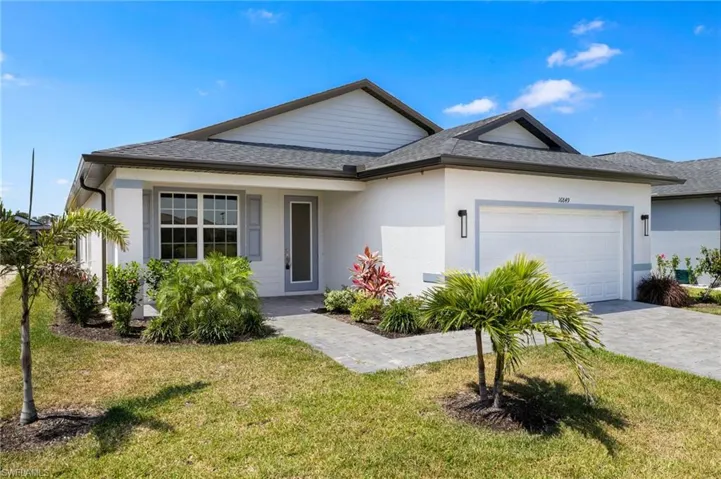 Single story home with a front yard, a garage, decorative driveway, a shingled roof, and stucco siding