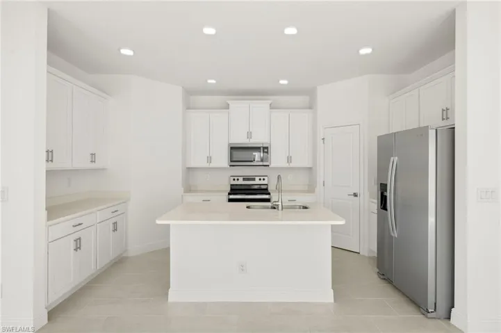 Kitchen featuring white cabinetry, appliances with stainless steel finishes, an island with sink, and a sink