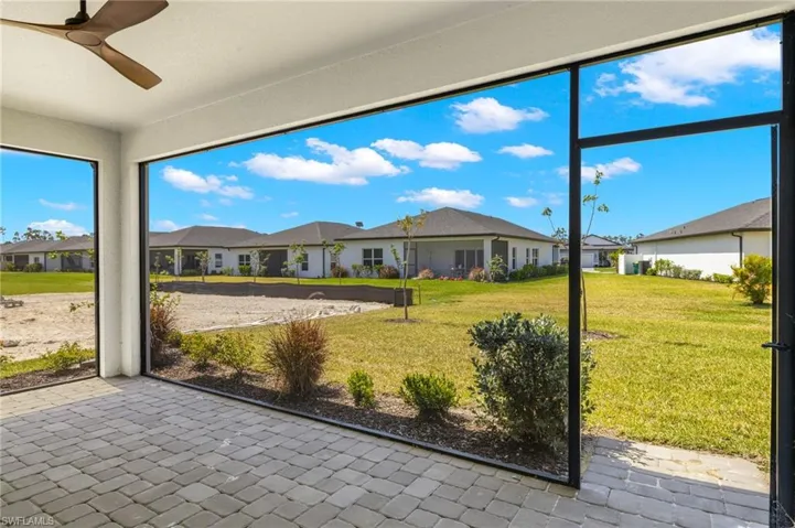 Unfurnished sunroom featuring ceiling fan and a residential view